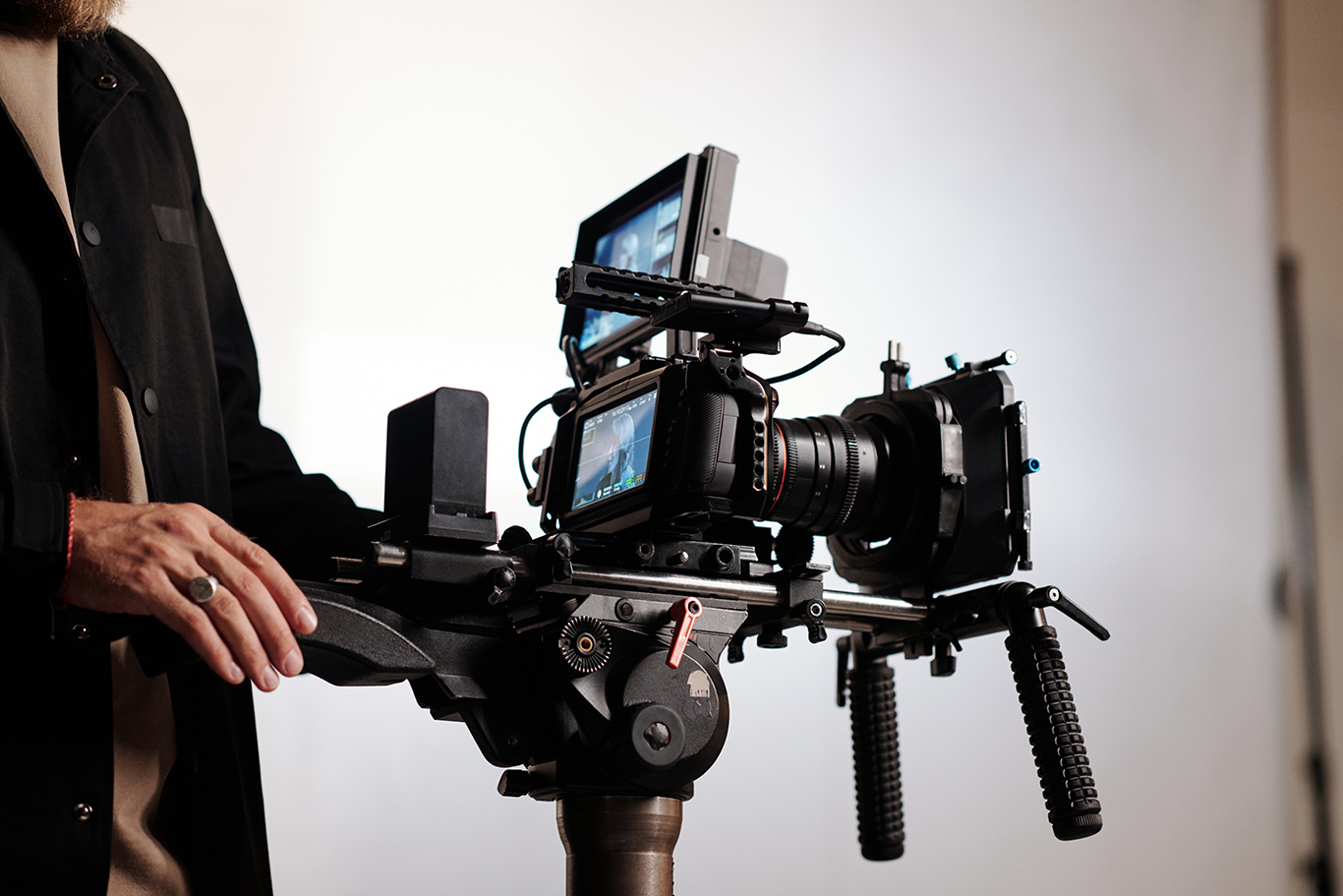 Close-up of cameraman or director of shooting team using steadicam while standing in studio and working over creation of commercial